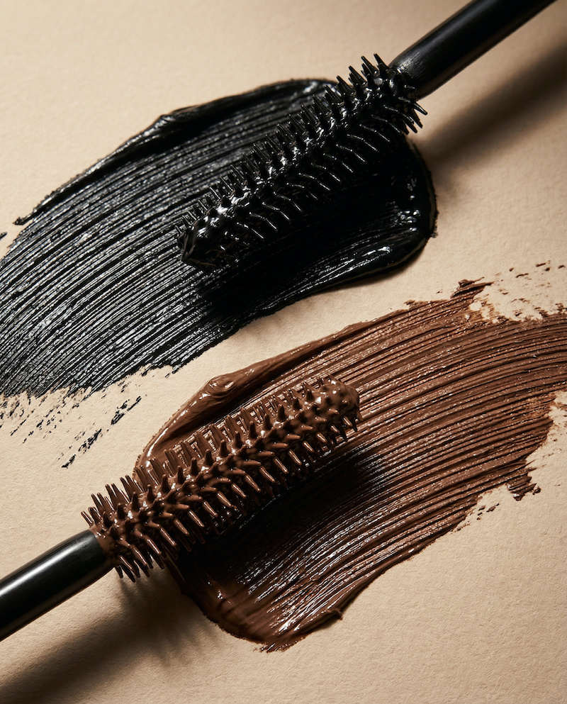 black and brown mascara swatches with applicators on the beige background, black paint, brush strokes, cosmetics textures, mascara, eyebrow mascara