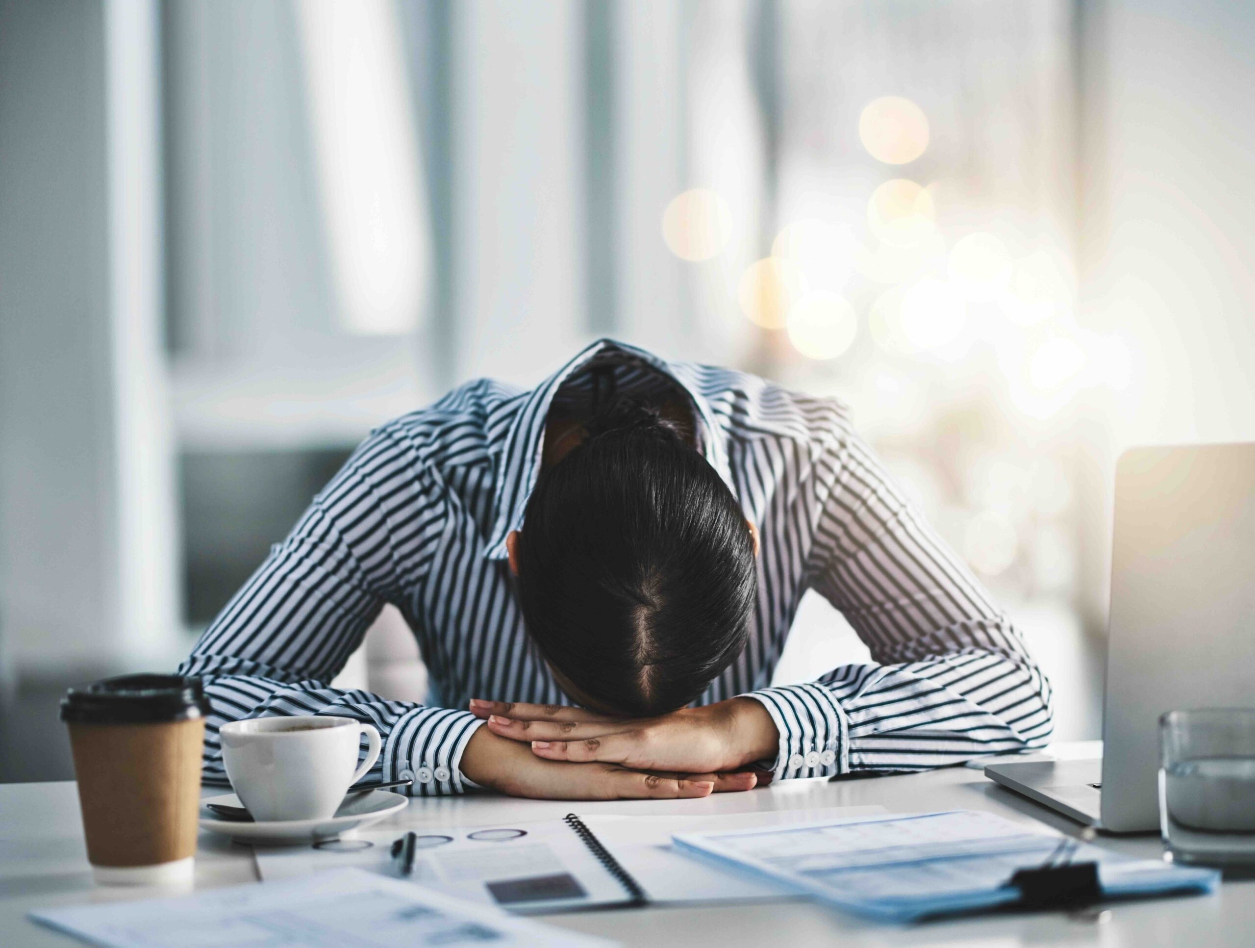 stanchezza-da-scrivania-donna-appoggiata-scrivania-stanca